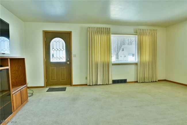 Carpeted entrance foyer with visible vents, baseboards, and a healthy amount of sunlight | Image 9