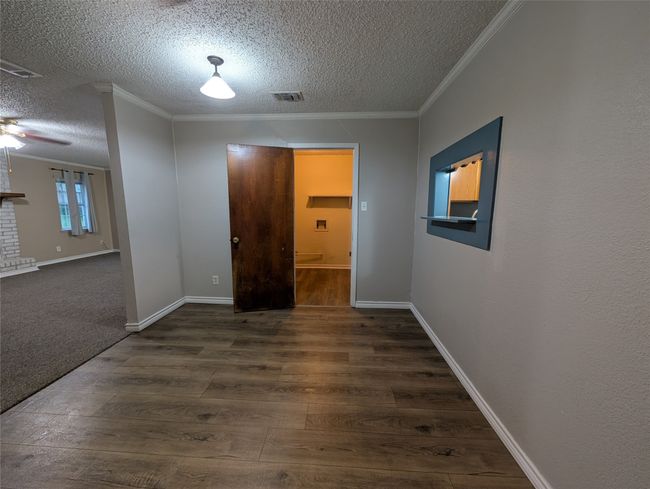Empty room featuring crown molding, wood finished floors, a textured ceiling, and visible vents | Image 11