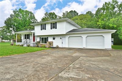 Tri-level home featuring a garage, a porch, and a front yard | Image 3