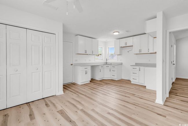 Kitchen featuring white cabinetry, a ceiling fan, a sink, and light wood finished floors | Image 5