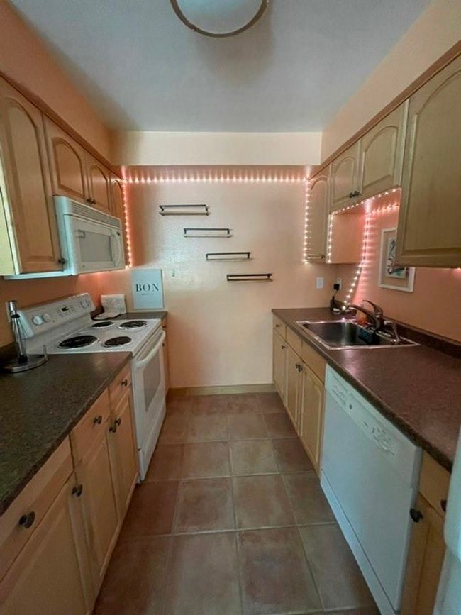 Kitchen with a sink, light tile patterned flooring, stove, dark countertops, and dishwasher | Image 15