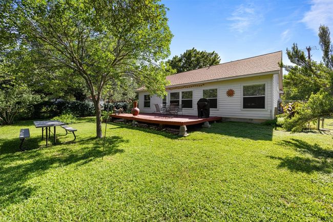 Rear view of property with a wooden deck, a lawn, and roof with shingles | Image 26