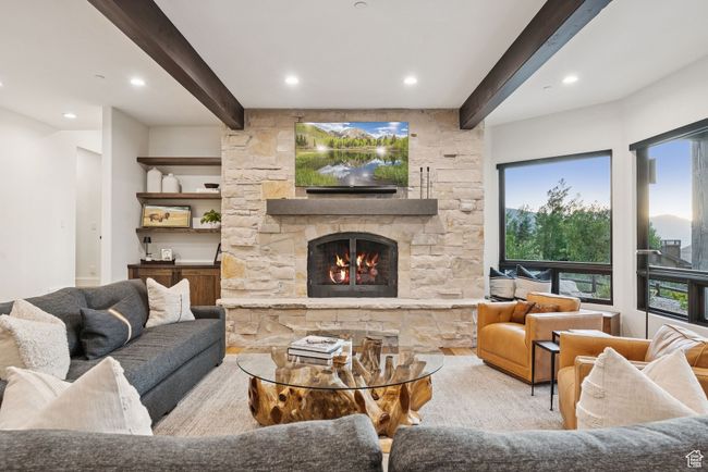 Living room featuring beam ceiling, a stone fireplace, and recessed lighting | Image 15