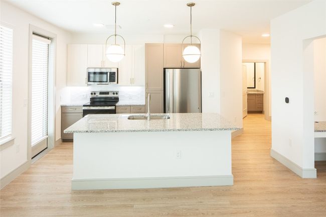 Kitchen featuring light wood-style floors, a center island with sink, stainless steel appliances, and a sink | Image 16