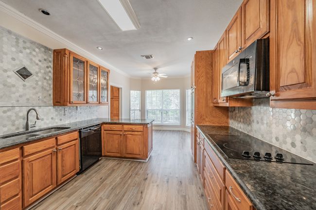 Kitchen featuring black appliances, crown molding, sink, ceiling fan, and light wood-type flooring | Image 6