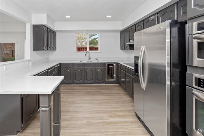 Kitchen featuring beverage cooler, light wood-type flooring, a sink, and stainless steel appliances | Image 8