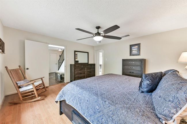 Spacious bedroom with hardwood floors, ceiling fan, and ample natural light. | Image 9