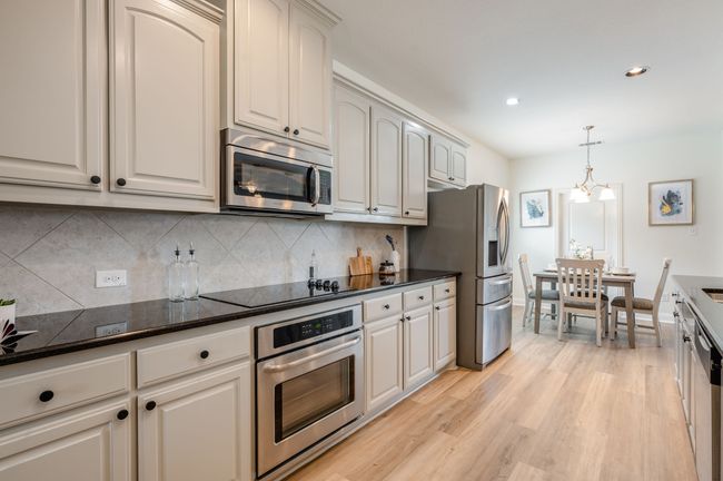 Kitchen featuring stainless steel appliances, light wood-style floors, decorative backsplash, pendant lighting, and recessed lighting | Image 8