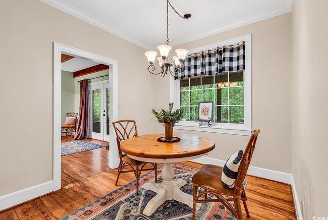 Dining space with ornamental molding, a chandelier, and light wood finished floors | Image 7
