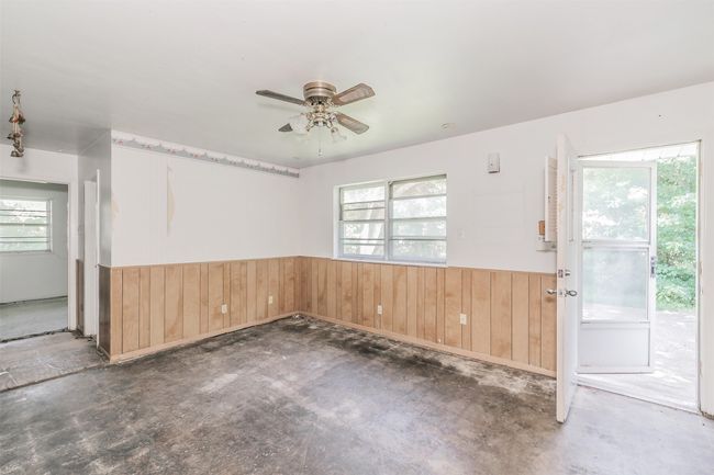 Spare room with wainscoting, wood walls, unfinished concrete floors, and a ceiling fan | Image 16