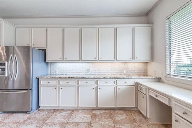 View of the back yard from this convenient desk space. Check out the abundance of cabinetry, beautiful tile back splash and granite counter top. | Image 19