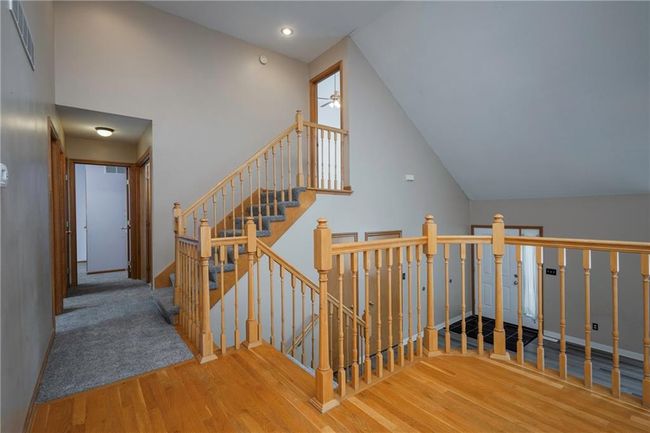Stairs with wood finished floors, a ceiling fan, lofted ceiling, and baseboards | Image 16