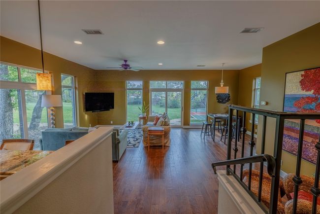 Large den featuring recessed lighting, hardwood flooring, full bar, game area, sitting area and a ceiling fan | Image 4