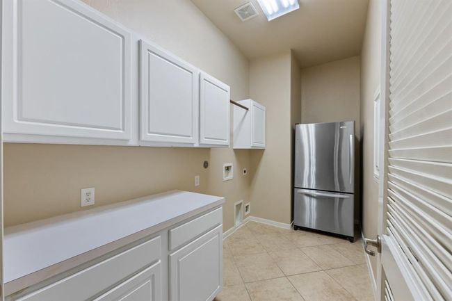 To the right of the foyer, next to the dining room, is the laundry room featuring tile floors, built-in cabinets, and counters. | Image 13