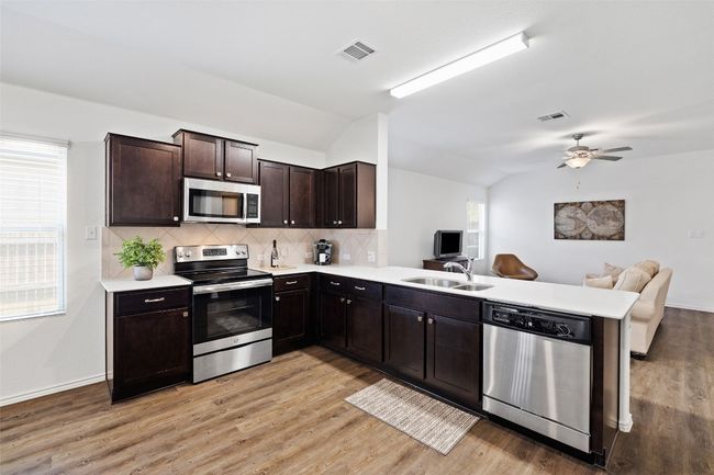 Kitchen featuring stainless steel appliances, lofted ceiling, open floor plan, a peninsula, and light countertops | Image 10