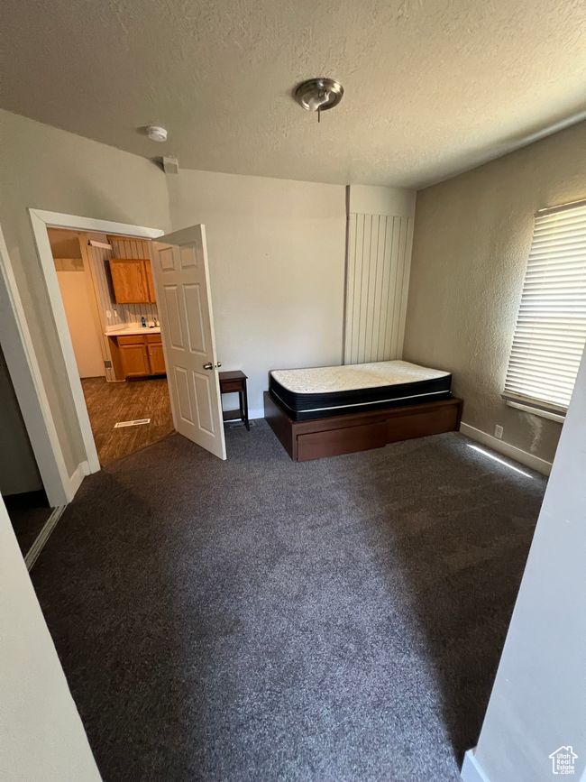 Unfurnished bedroom featuring baseboards, dark carpet, and a textured ceiling | Image 7