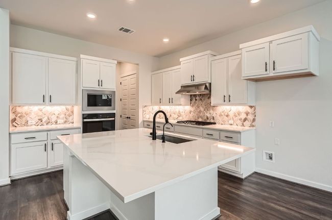 Kitchen featuring stainless steel appliances, a sink, under cabinet range hood, tasteful backsplash, and dark wood-style floors | Image 11