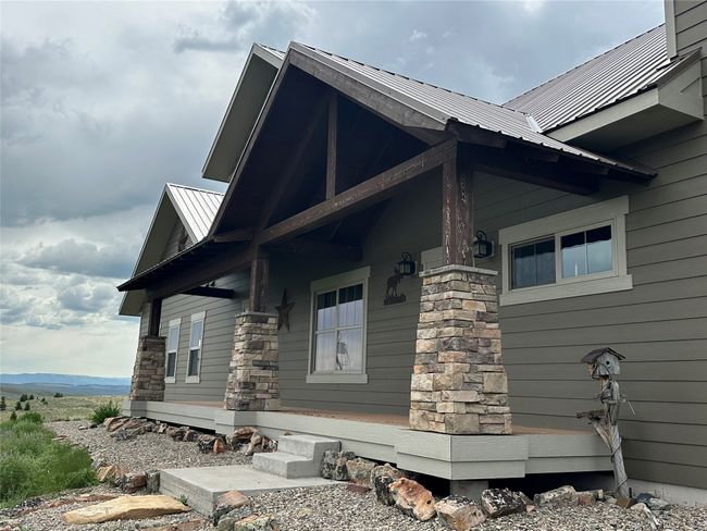 View of side of home with a metal roof, stone siding, a standing seam roof, and covered porch | Image 30