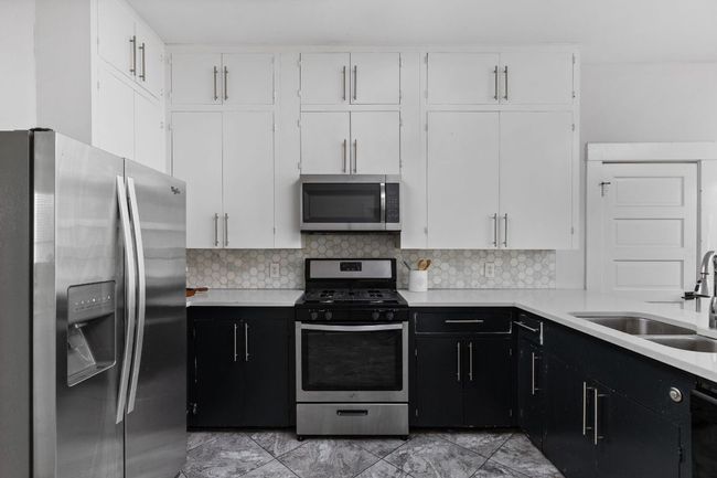 Kitchen with white cabinets, a sink, light countertops, stainless steel appliances, and dark cabinetry | Image 13
