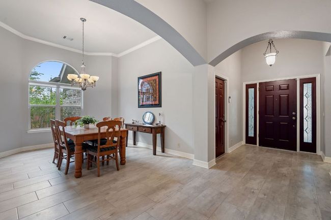 Dining room with a towering ceiling, visible vents, arched walkways, light wood-type flooring, and a chandelier | Image 9