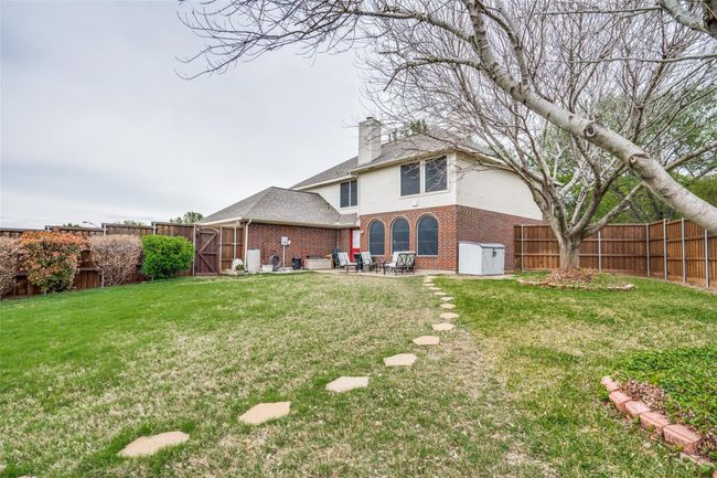 Rear view of property featuring brick siding, a chimney, a fenced backyard, and a patio area | Image 32