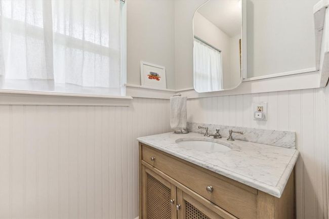 Elegant and modern half bath with beadboard detailing, perfect for guests. | Image 17