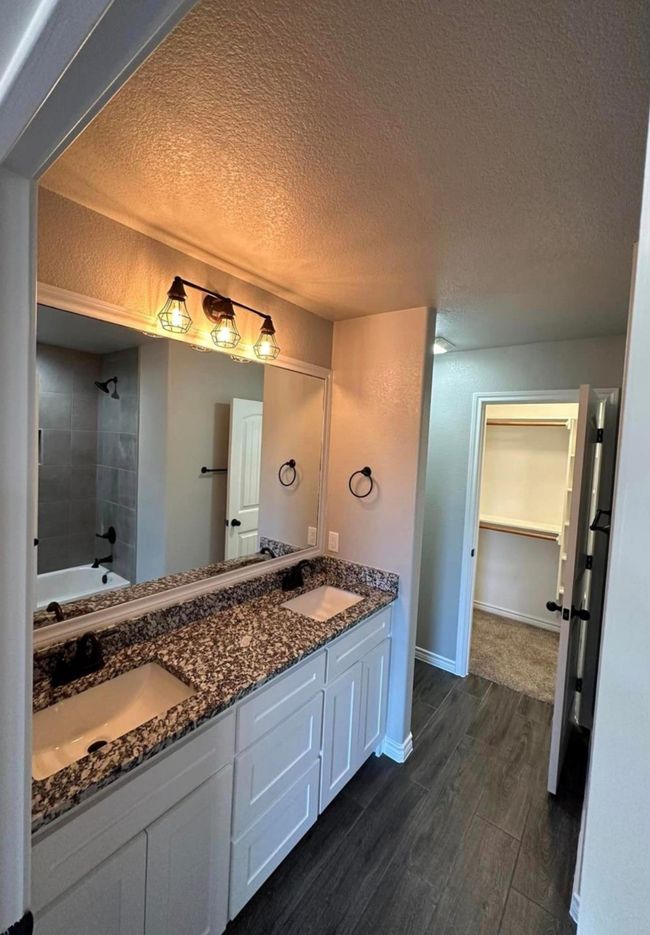 Full bathroom with wood finished floors, double vanity, a textured ceiling, and shower / bathtub combination | Image 7