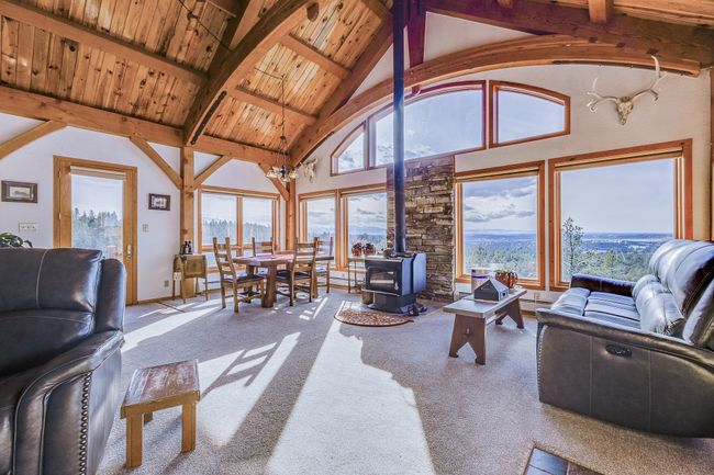 Carpeted living area with high vaulted ceiling, wooden ceiling, a wood stove, and beam ceiling | Image 5