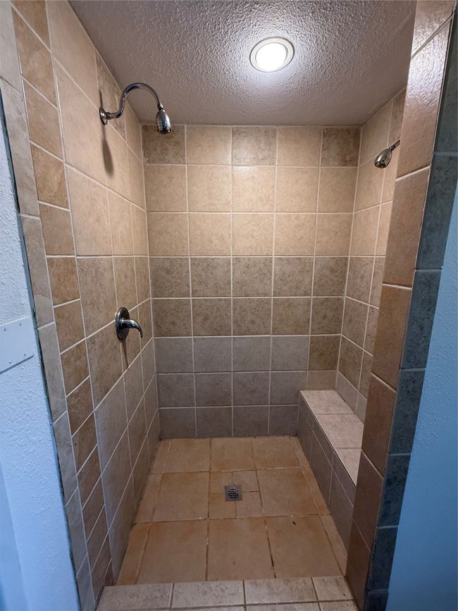 Bathroom with a stall shower, a textured ceiling, and light tile patterned floors | Image 19