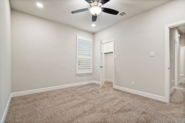 Unfurnished bedroom with light carpet, a walk in closet, ceiling fan, and recessed lighting | Image 18