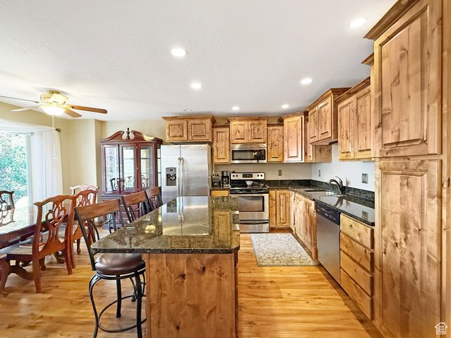 Kitchen with a breakfast bar, appliances with stainless steel finishes, a kitchen island, recessed lighting, and light wood-style floors | Image 5
