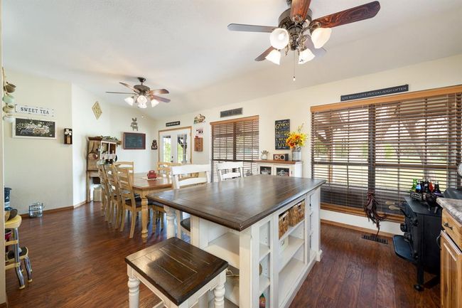 Dining room with dark wood-type flooring, baseboards, lofted ceiling, and ceiling fan | Image 14