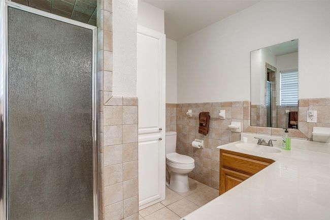Full bathroom with tile patterned flooring, tile walls, a shower stall, vanity, and wainscoting | Image 25