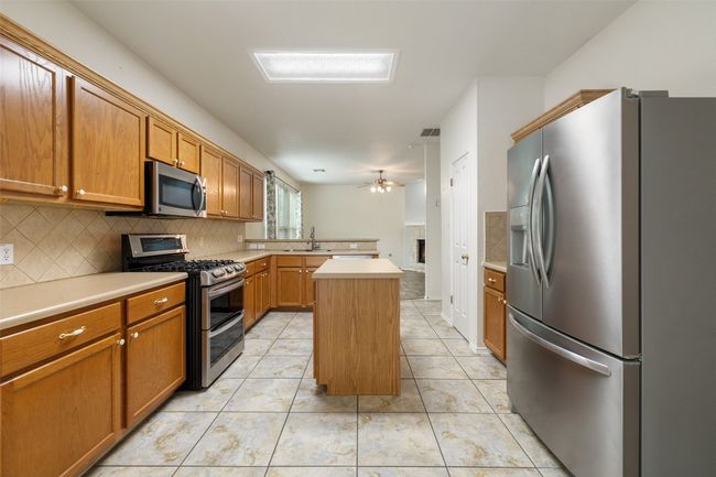 Kitchen featuring a sink, ceiling fan, tasteful backsplash, and stainless steel appliances | Image 9