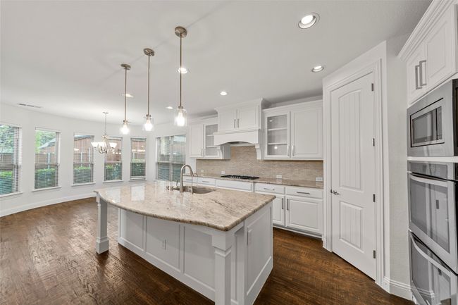Kitchen featuring dark wood-style flooring, a sink, stainless steel appliances, white cabinetry, and backsplash | Image 7