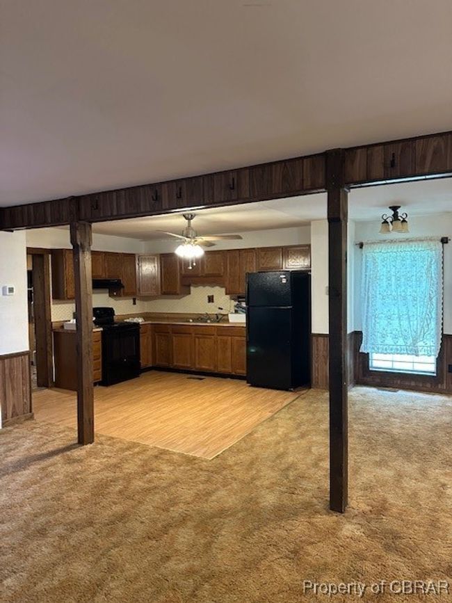 Kitchen featuring fridge, stove, light colored carpet, a ceiling fan, and wooden walls | Image 12