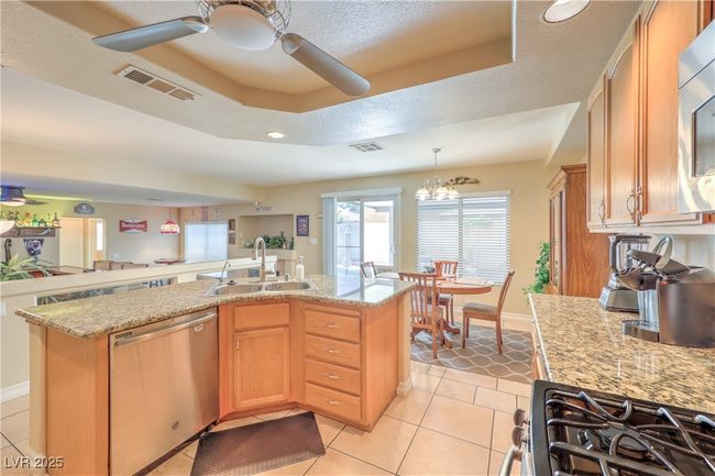 Kitchen featuring dishwasher, a raised ceiling, a ceiling fan, light tile patterned flooring, and decorative light fixtures | Image 28