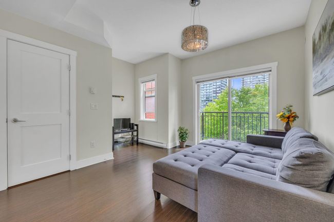 Living area with a baseboard radiator, dark wood-type flooring, and baseboards | Image 10