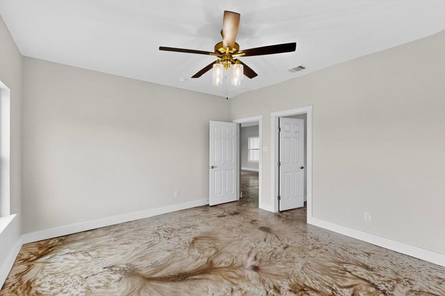 Unfurnished bedroom with concrete flooring and ceiling fan | Image 28