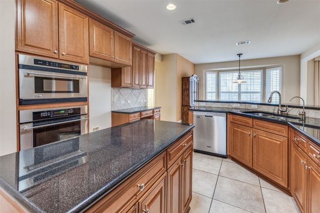 Kitchen featuring visible vents, a sink, brown cabinetry, and appliances with stainless steel finishes | Image 8