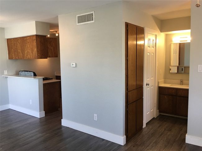 Kitchen featuring visible vents, a sink, baseboards, light countertops, and dark wood-style floors | Image 4