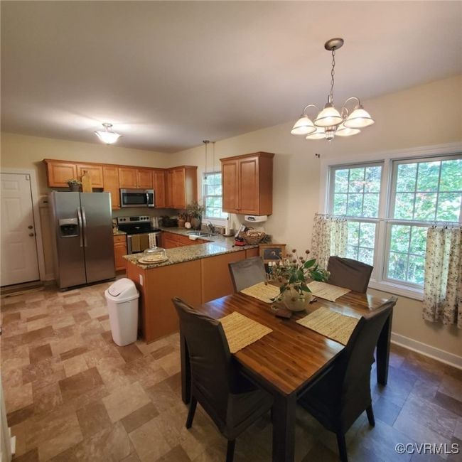 Dining room with a notable chandelier, baseboards, and stone finish flooring | Image 15