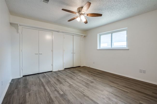 Unfurnished bedroom with wood finished floors, a textured ceiling, and a ceiling fan | Image 18