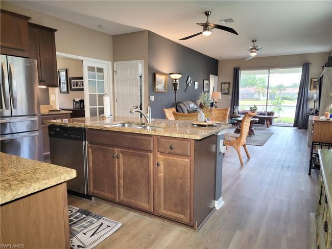 Kitchen with an island with sink, stainless steel appliances, a ceiling fan, a sink, and light wood-style flooring | Image 10