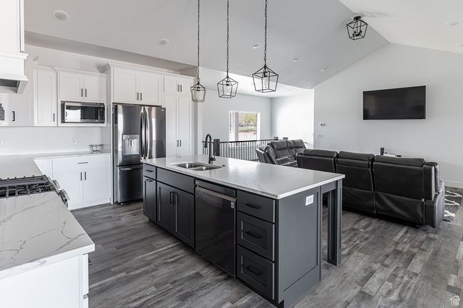 Kitchen with a sink, appliances with stainless steel finishes, open floor plan, vaulted ceiling, and dark wood-type flooring | Image 7
