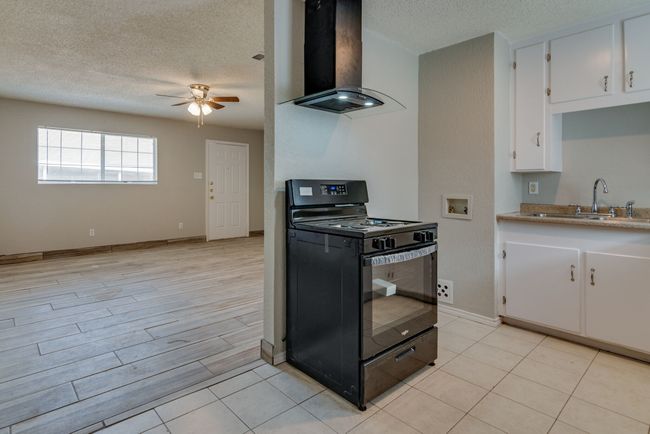 Kitchen with a sink, ceiling fan, a textured ceiling, extractor fan, and black gas range oven | Image 11