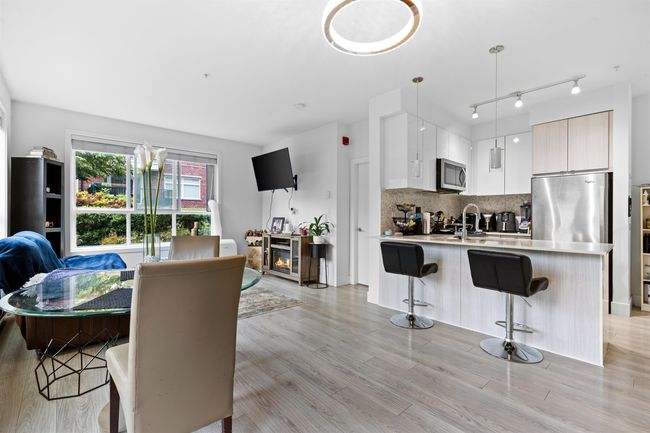 Kitchen with appliances with stainless steel finishes, modern cabinets, a breakfast bar area, light countertops, and light wood-style floors | Image 15