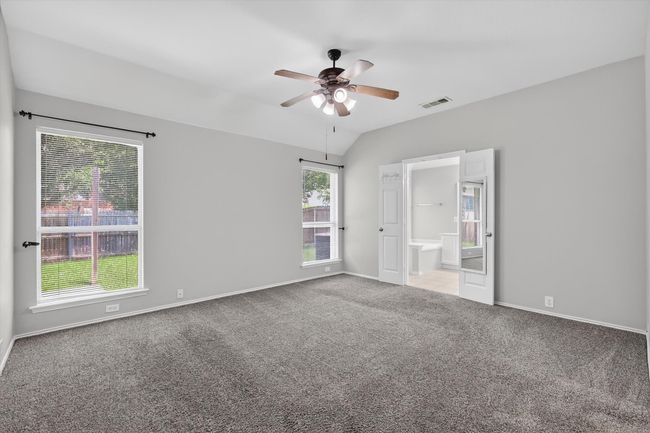 Carpeted primary bedroom with a ceiling fan and lofted ceiling | Image 12