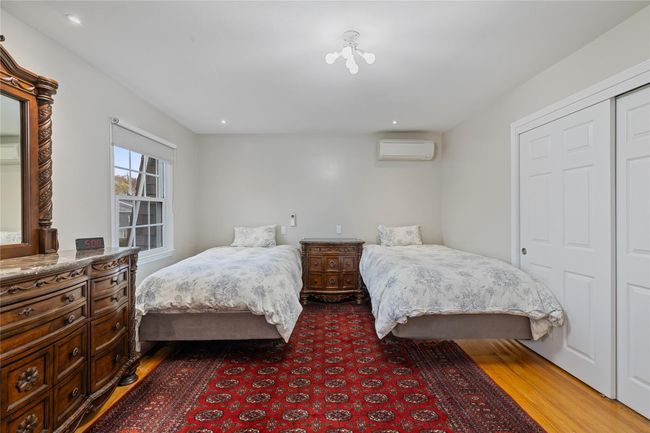 Bedroom featuring a wall mounted air conditioner, recessed lighting, wood finished floors, and a closet | Image 23