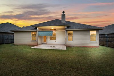 Back house at dusk featuring a patio and a yard | Image 3